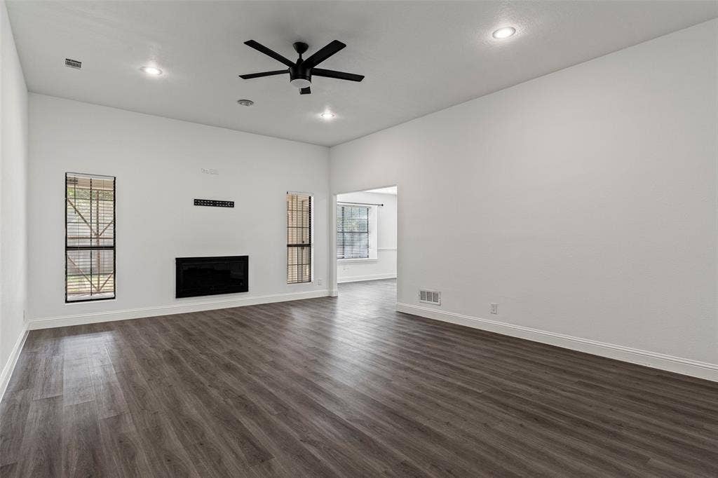 4128 Woodenrail Lane, Irving, TX 75061 Spacious interior featuring wood-finish flooring, high ceilings with recessed lighting, a matte black ceiling fan, and a built-in electric fireplace