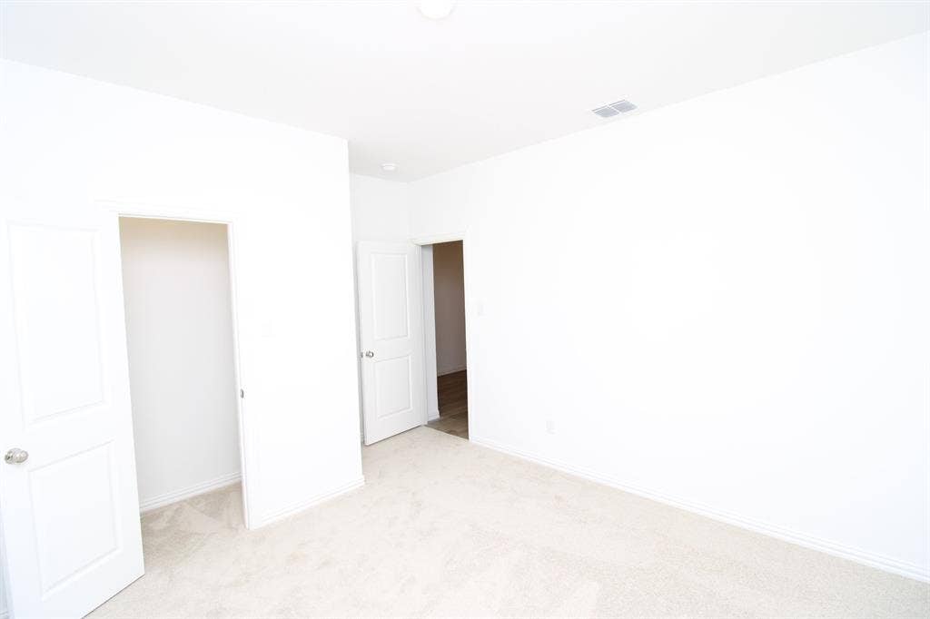 Neutral interior space featuring wall-to-wall carpeting, white walls, and interior doors with brushed metal hardware