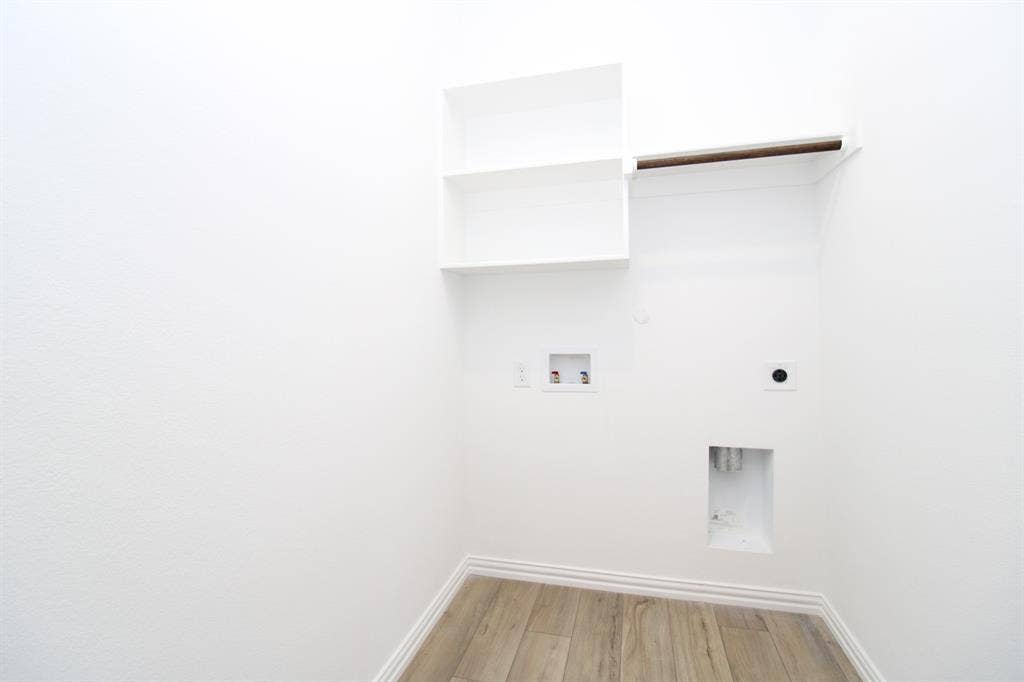 Utility area featuring wood-finish flooring, built-in white shelving, and an integrated hanging rod