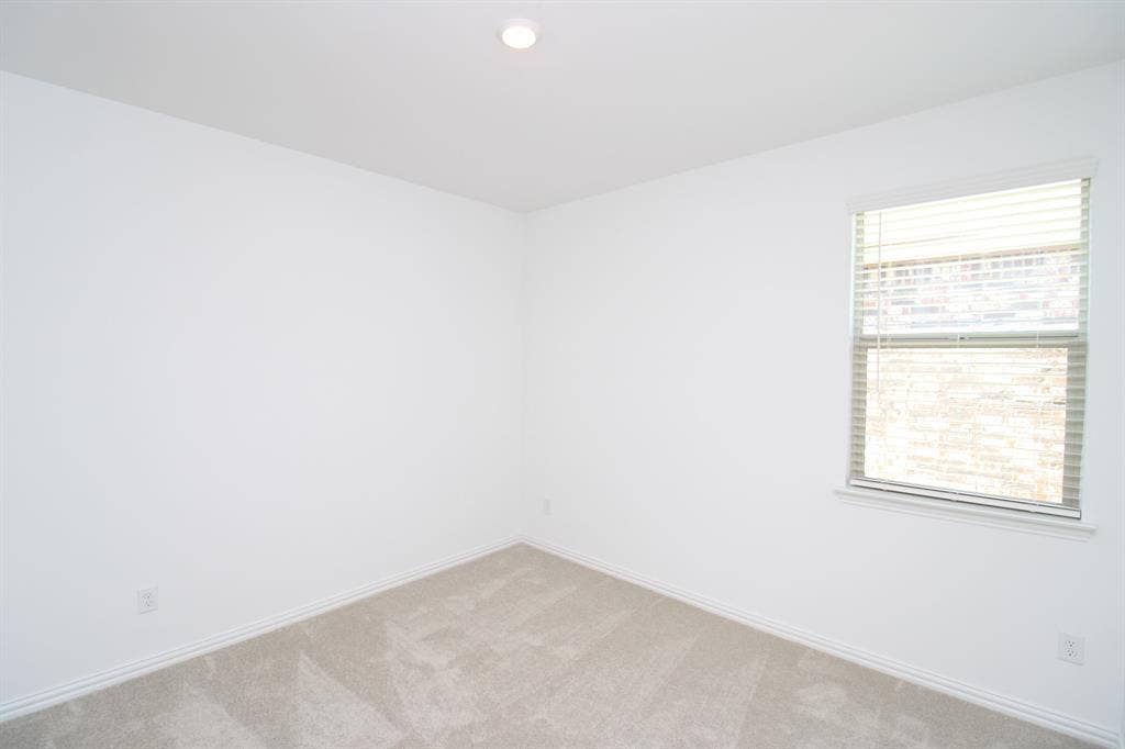Neutral-toned wall paint, plush carpeting, recessed lighting, and a single-hung window featuring horizontal blinds