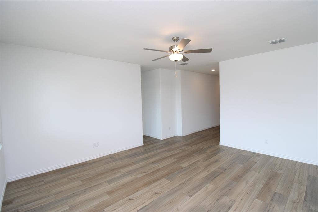 Neutral wall finishes, wood-finish flooring, and a multi-blade ceiling fan with an integrated light fixture