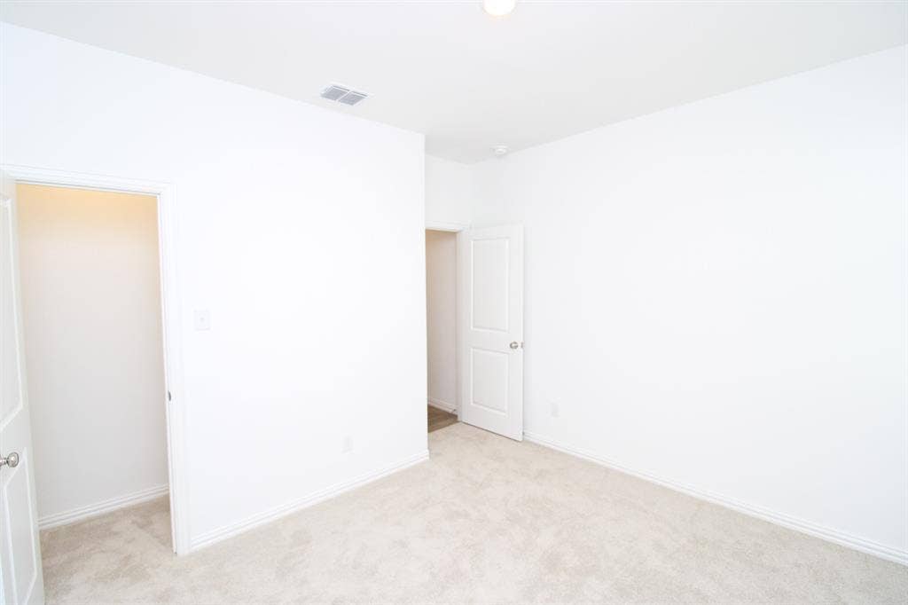 Neutral interior featuring light-toned wall-to-wall carpeting and solid-core interior doors with metallic lever hardware