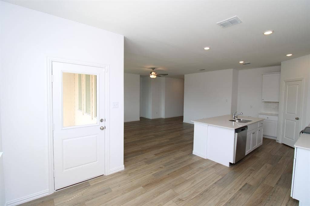 Kitchen featuring a central island with a neutral countertop and stainless steel dishwasher, wood-finish flooring, recessed lighting, and a glass-paneled exterior door