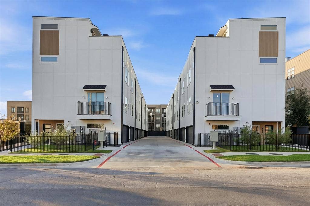 4319 San Jacinto Street, #101, Dallas, TX 75204 Contemporary multi-level residential structures featuring smooth white stucco facades, metal railing balconies, integrated garage entries, and wood-finish panel accents