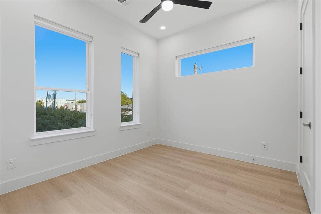 4319 San Jacinto Street, #101, Dallas, TX 75204 Room featuring wood-finish flooring, recessed lighting, matte black ceiling fan, and multiple windows including a rectangular clerestory window