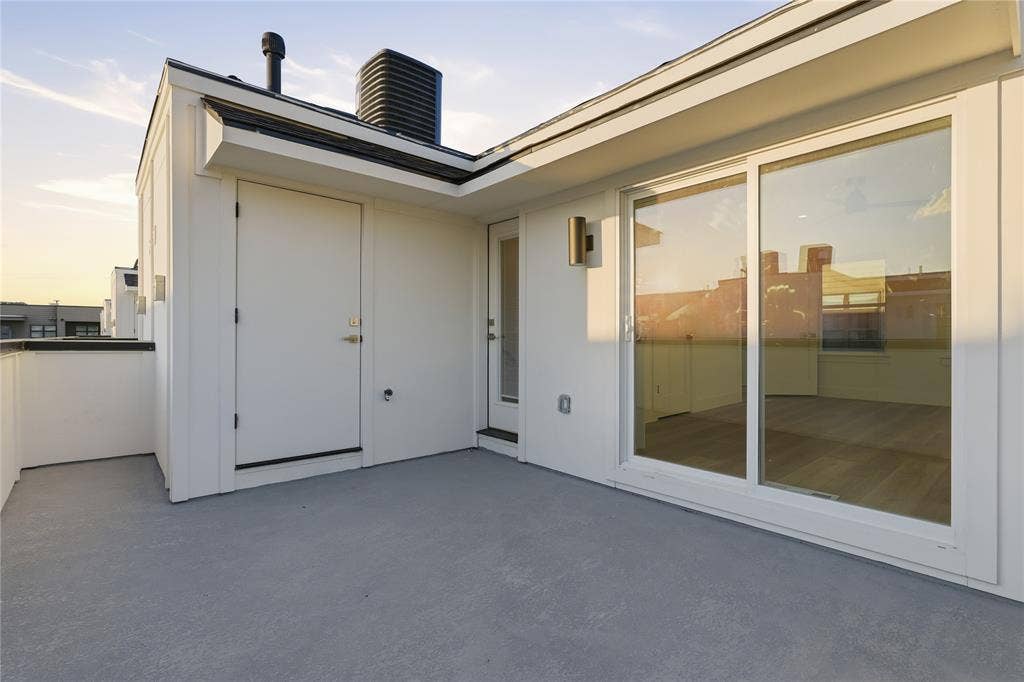 4319 San Jacinto Street, #101, Dallas, TX 75204 Rooftop terrace featuring concrete flooring, sliding glass door, exterior wall-mounted lighting, and neutral-toned siding