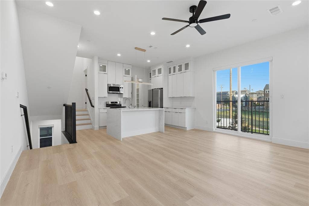 4319 San Jacinto Street, #101, Dallas, TX 75204 Open-concept interior featuring light wood-finish flooring, white shaker-style cabinetry, a central kitchen island, recessed lighting, and a sliding glass door