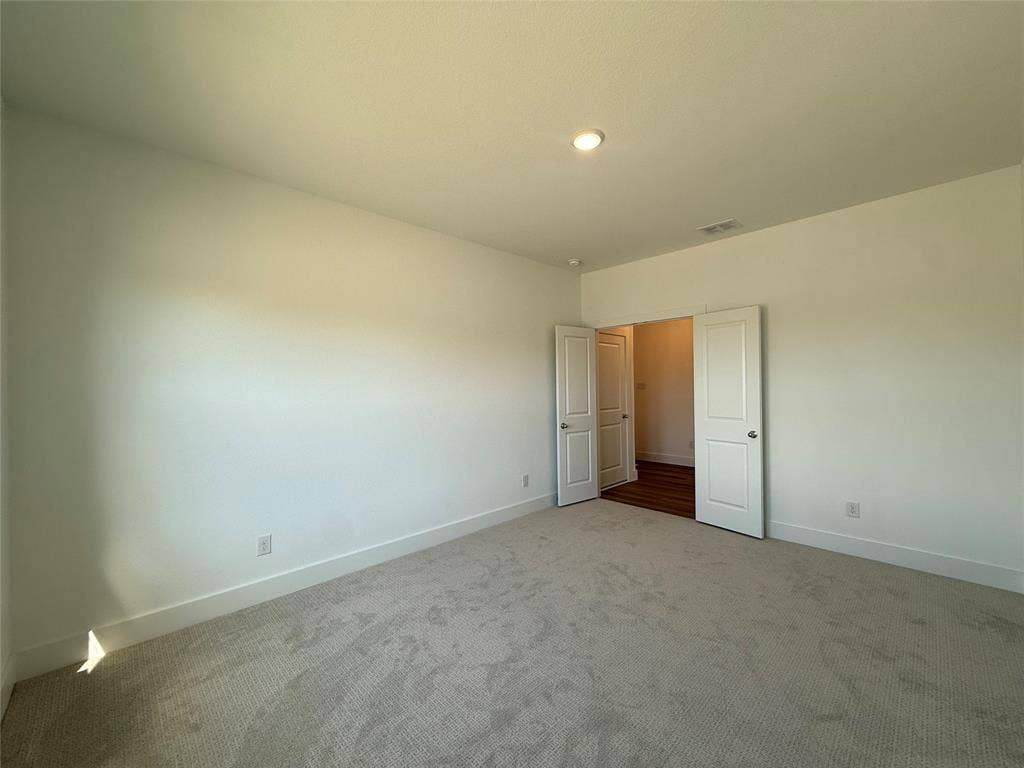 Neutral interior room featuring neutral carpeting, white wall finishes, and double doors