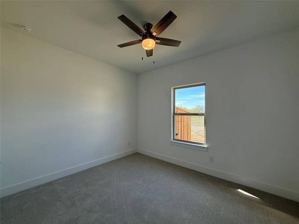 Neutral-toned wall finish, wall-to-wall carpeting, single-hung window with exterior view, and ceiling fan with integrated light fixture