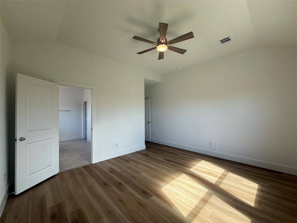 Vaulted ceiling featuring a central five-blade ceiling fan with integrated lighting and wood-finish flooring