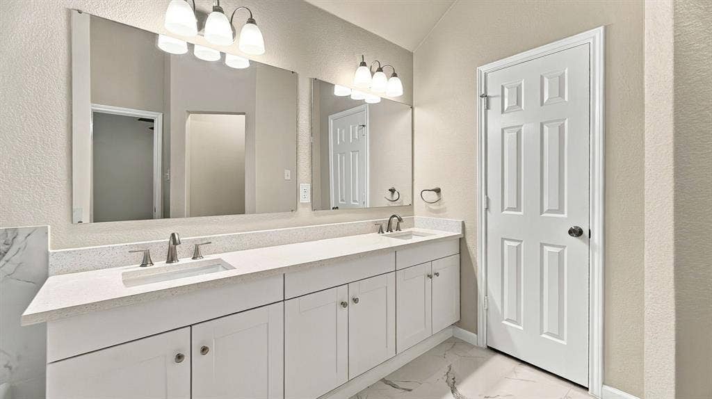 Kitchen featuring white cabinetry, light-toned stone-finish countertops, stainless steel undermount sink with arched pull-down faucet, white subway tile backsplash, and wood-finish flooring