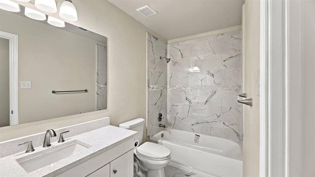 Dual-sink vanity featuring stone-composite countertops, shaker-style cabinetry, undermount sinks, and wall-mounted multi-bulb lighting fixtures