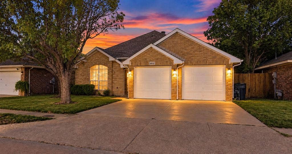 Single-story brick exterior featuring a front-facing attached two-car garage, arched window, and concrete driveway