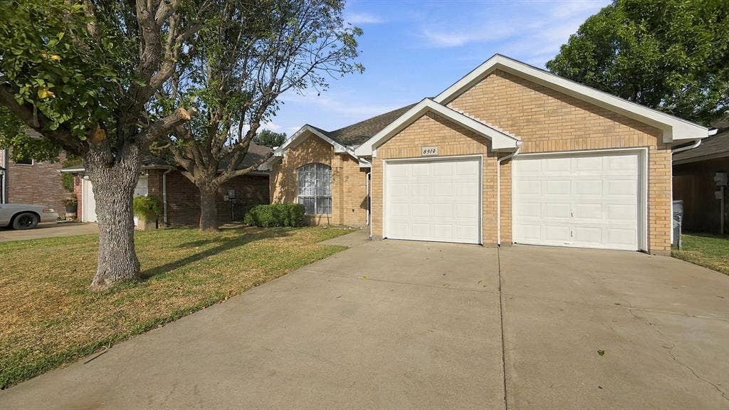 Brick exterior facade featuring a double-car garage with two overhead doors, arched window detail, and concrete driveway