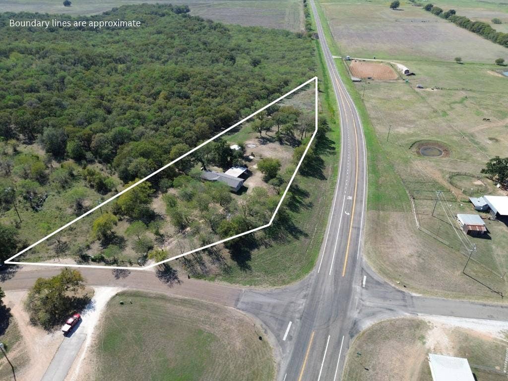 3907 Rogers Hill Road, Waco, TX 76705 Aerial perspective of a corner lot featuring mature trees, wooded acreage, and paved road access