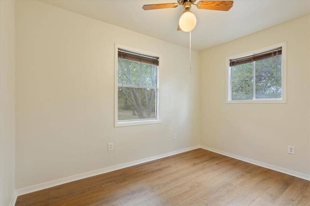 3907 Rogers Hill Road, Waco, TX 76705 Neutral-toned room featuring wood-finish flooring, two sliding windows, and a ceiling fan with integrated lighting