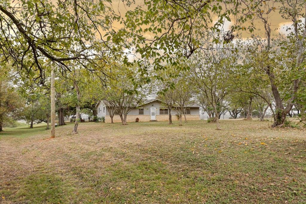 3907 Rogers Hill Road, Waco, TX 76705 Expansive lot featuring mature trees and a single-story residence with light-toned horizontal siding and stone masonry exterior