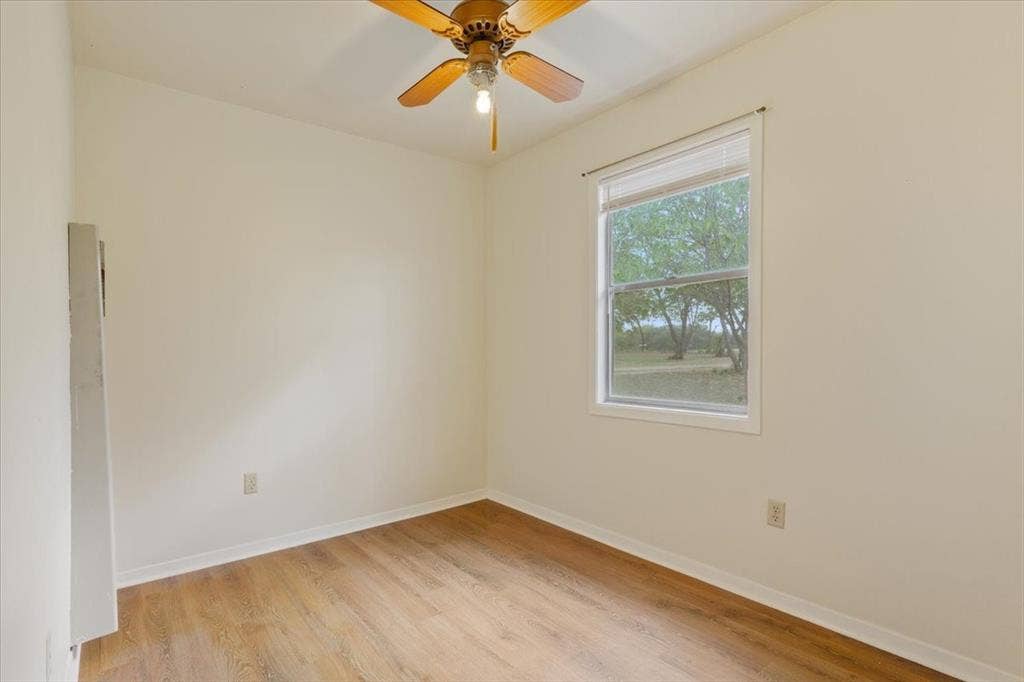 3907 Rogers Hill Road, Waco, TX 76705 Interior room featuring wood-finish flooring, a ceiling fan with integrated lighting, and a window with wood-frame trim