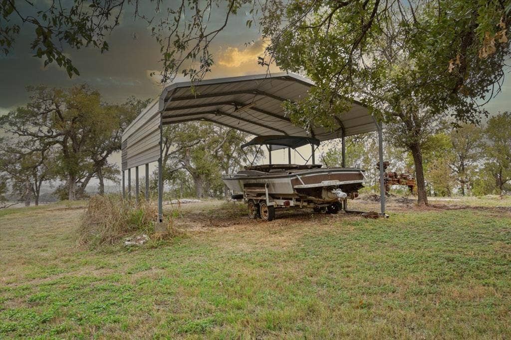 3907 Rogers Hill Road, Waco, TX 76705 Freestanding metal carport structure with a gabled roof, supported by steel posts on a grass-covered lot featuring mature trees