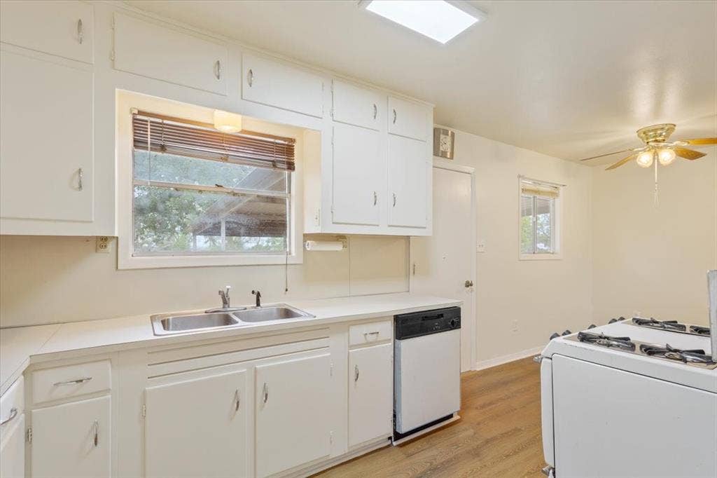 3907 Rogers Hill Road, Waco, TX 76705 Kitchen featuring white cabinetry with overhead storage, a double-basin stainless steel sink, wood-finish flooring, and a ceiling-mounted light fixture