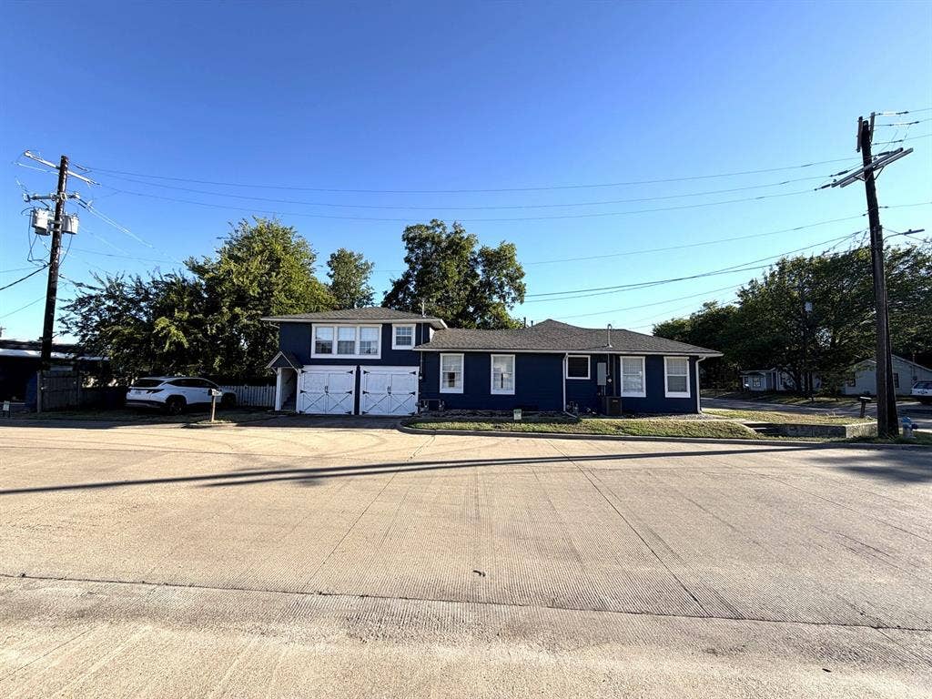 201 S Jones Street, Granbury, TX 76048 Exterior facade featuring dark-toned siding, white trim, a multi-section roofline, and dual garage doors
