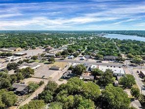 201 S Jones Street, Granbury, TX 76048 Aerial perspective featuring mature trees, paved roadways, and proximity to a large body of water