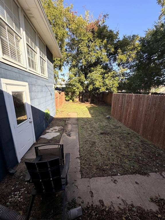 201 S Jones Street, Granbury, TX 76048 Private backyard featuring a grass lawn, perimeter wood fencing, concrete walkway, and mature trees