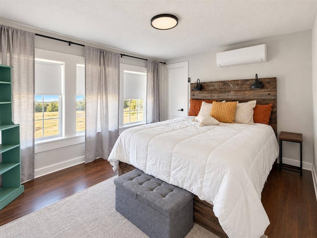 201 S Jones Street, Granbury, TX 76048 Wood-finish flooring, white paneled walls, multi-pane windows, wall-mounted heating and cooling unit, and flush-mount ceiling lighting