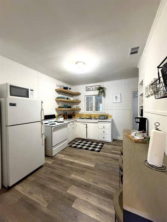 201 S Jones Street, Granbury, TX 76048 Kitchen featuring wood-finish flooring, white cabinetry, open wooden shelving, and a dual-basin sink with a window backsplash