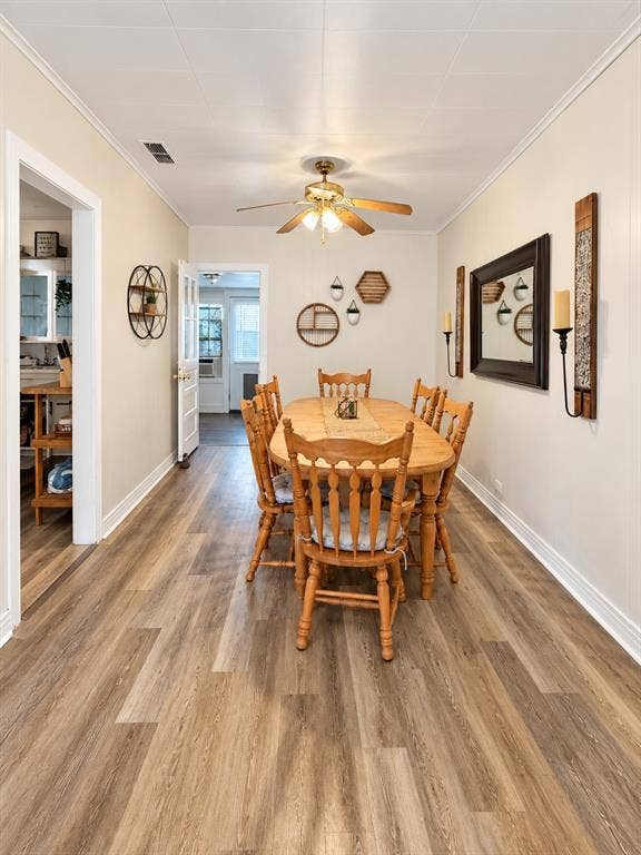 201 S Jones Street, Granbury, TX 76048 Dining area featuring wood-finish flooring, crown molding, and a central ceiling fan with integrated lighting