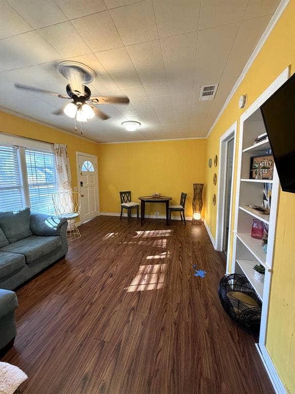 201 S Jones Street, Granbury, TX 76048 Living space featuring wood-finish flooring, built-in shelving, a ceiling fan with integrated lighting, and a multi-pane glass entry door
