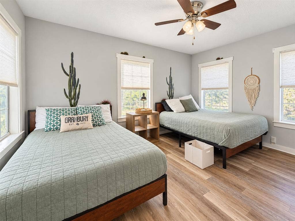 201 S Jones Street, Granbury, TX 76048 Neutral-toned walls, wood-finish flooring, multi-light ceiling fan, and large windows with integrated blinds