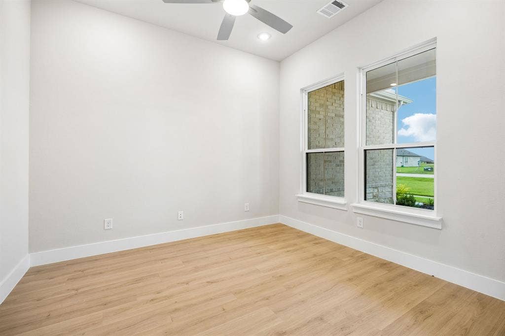 108 Swan Lake Drive, Waxahachie, TX 75165 Neutral-toned room featuring wood-finish flooring, dual-pane windows, and a ceiling-mounted fan with integrated light