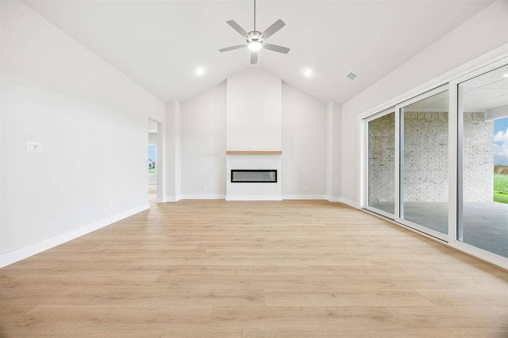 108 Swan Lake Drive, Waxahachie, TX 75165 Vaulted ceiling featuring a linear fireplace with wood-finish mantle, wood-finish flooring, recessed lighting, and expansive glass sliding doors