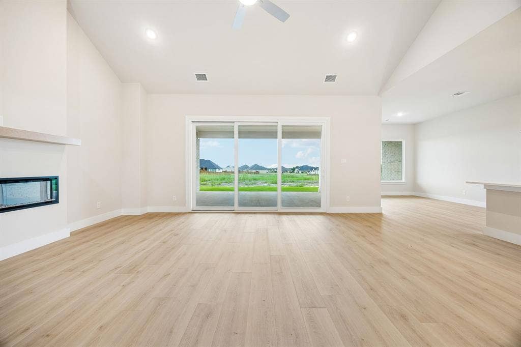 108 Swan Lake Drive, Waxahachie, TX 75165 Vaulted ceilings, wood-finish flooring, built-in horizontal fireplace, recessed lighting, and sliding glass doors with exterior landscape exposure