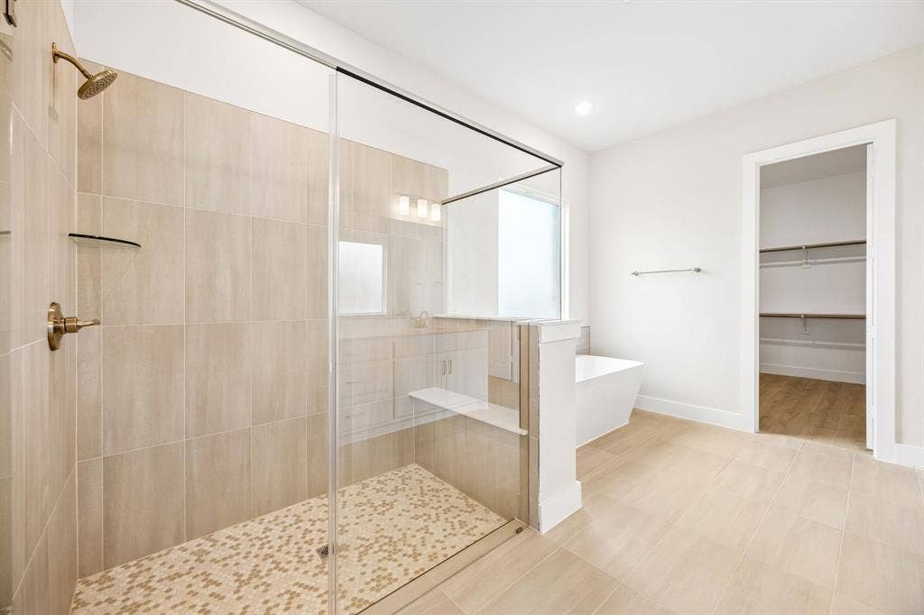 108 Swan Lake Drive, Waxahachie, TX 75165 Walk-in shower with floor-to-ceiling tile, frameless glass enclosure, built-in tiled bench, and gold-finish fixtures