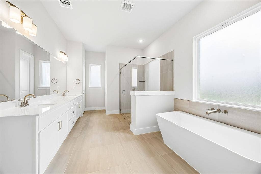108 Swan Lake Drive, Waxahachie, TX 75165 Double vanity with stone-surface countertop, freestanding soaking tub, glass-enclosed shower, and tile-finish flooring