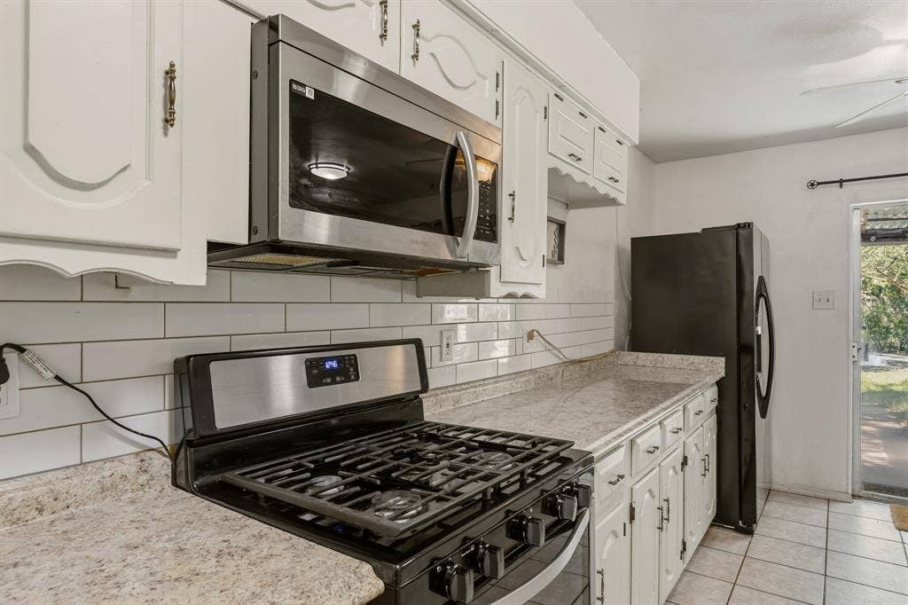 The kitchen has a gas range and a stainless steel microwave.