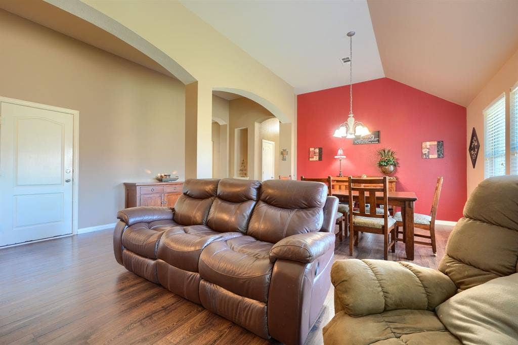 Vaulted ceilings, wood-finish flooring, architectural arched openings, and a prominent accent wall