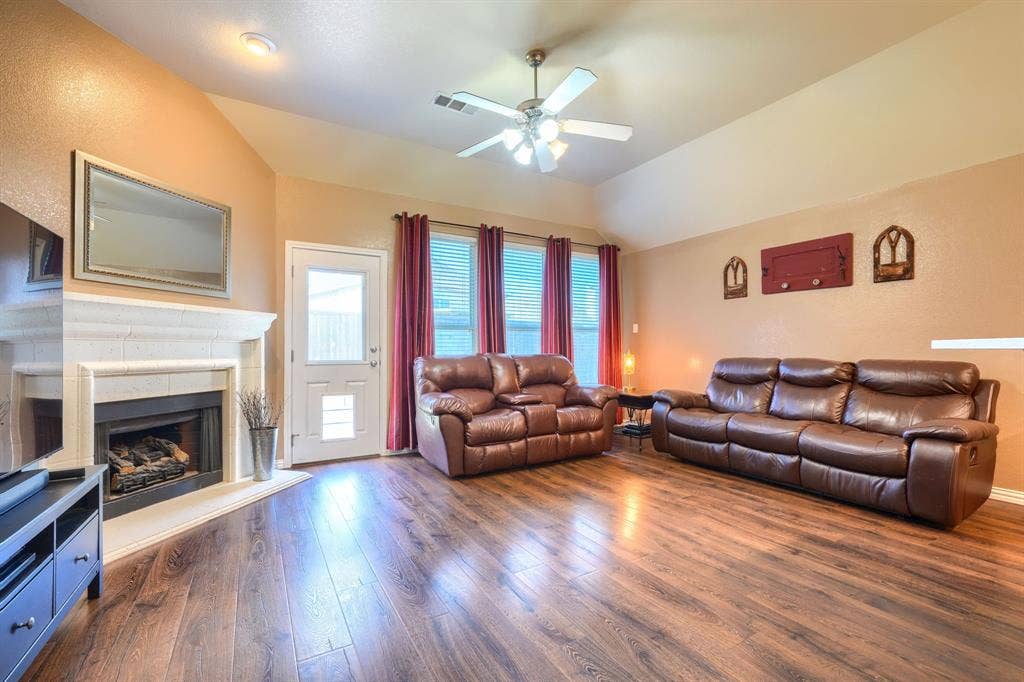 Vaulted ceilings, wood-finish flooring, and a stone-surround fireplace with a hearth