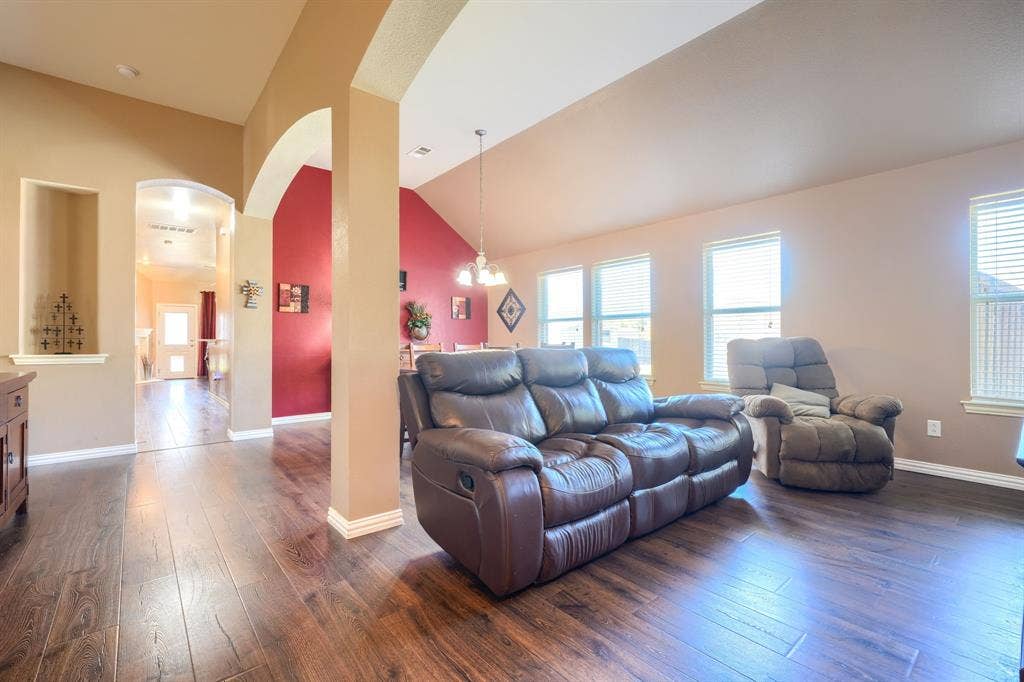 Vaulted ceilings, wood-finish flooring, architectural arched openings, and a built-in recessed wall niche