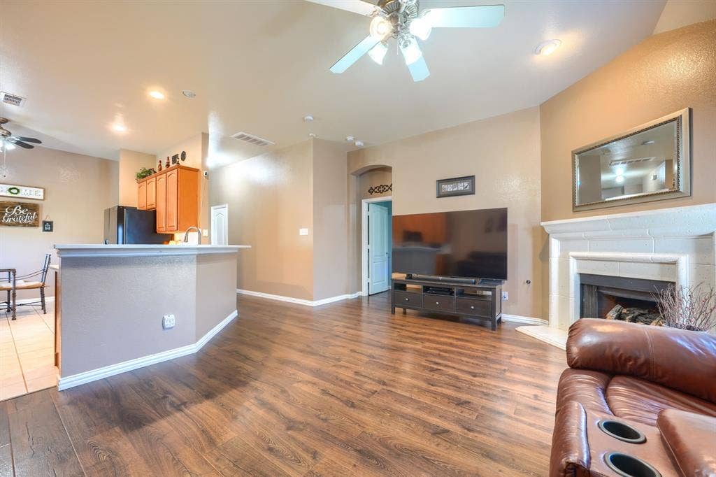 Living area featuring wood-finish flooring, a fireplace with a mantel, recessed lighting, a ceiling fan, and a kitchen peninsula