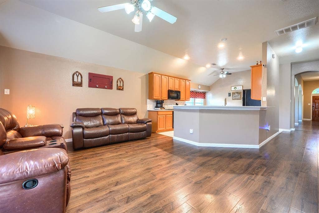 Vaulted ceilings, wood-finish flooring, recessed lighting, and kitchen cabinetry with a peninsula