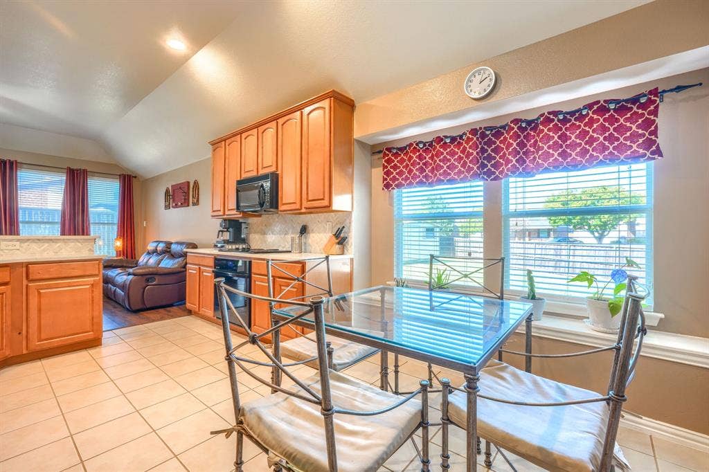 Kitchen featuring wood cabinetry, recessed lighting, and tile flooring, including a large window with a deep sill and a vaulted ceiling