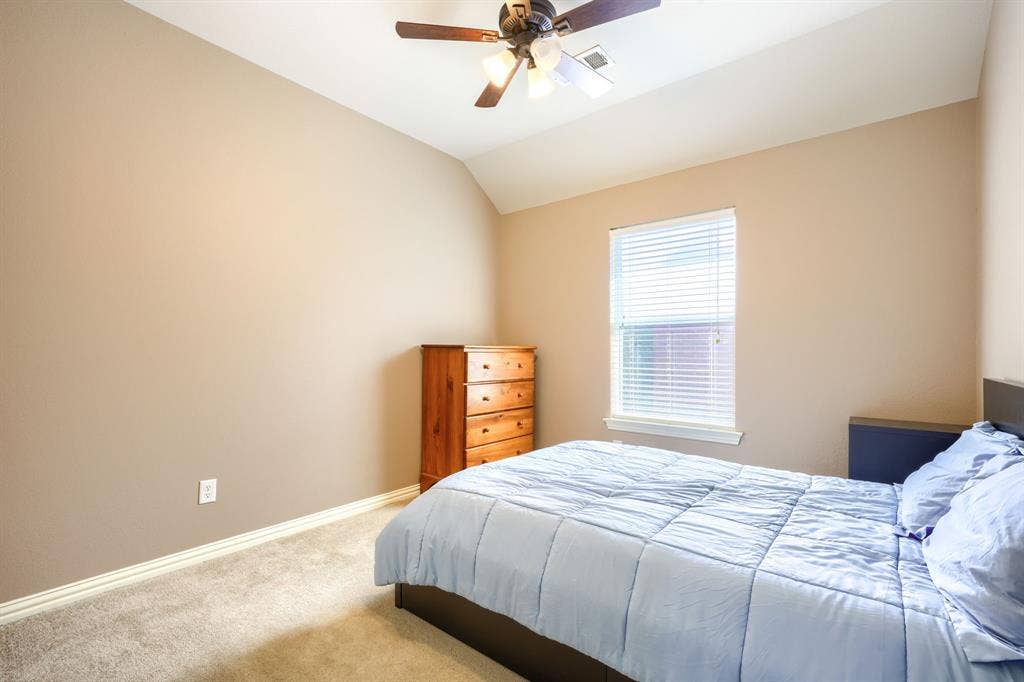 Vaulted ceiling featuring a central multi-light ceiling fan and a single-pane window with horizontal blinds