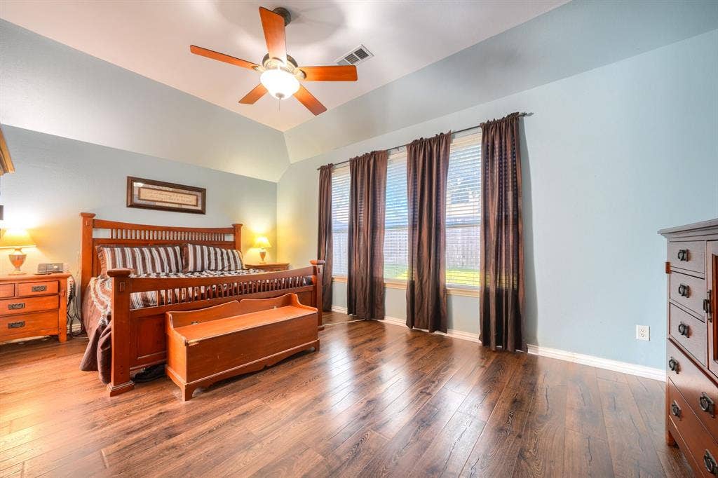 Vaulted ceilings, wood-finish flooring, and a multi-blade ceiling fan with integrated light fixture