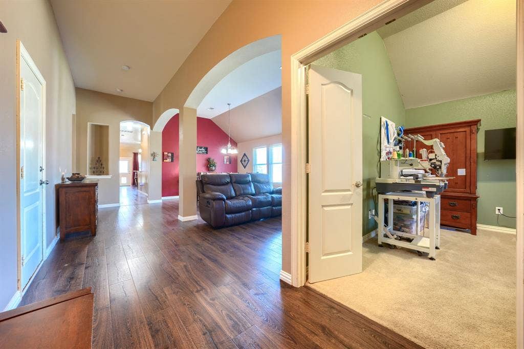 Interior hallway featuring wood-finish flooring, vaulted ceilings, and architectural archways