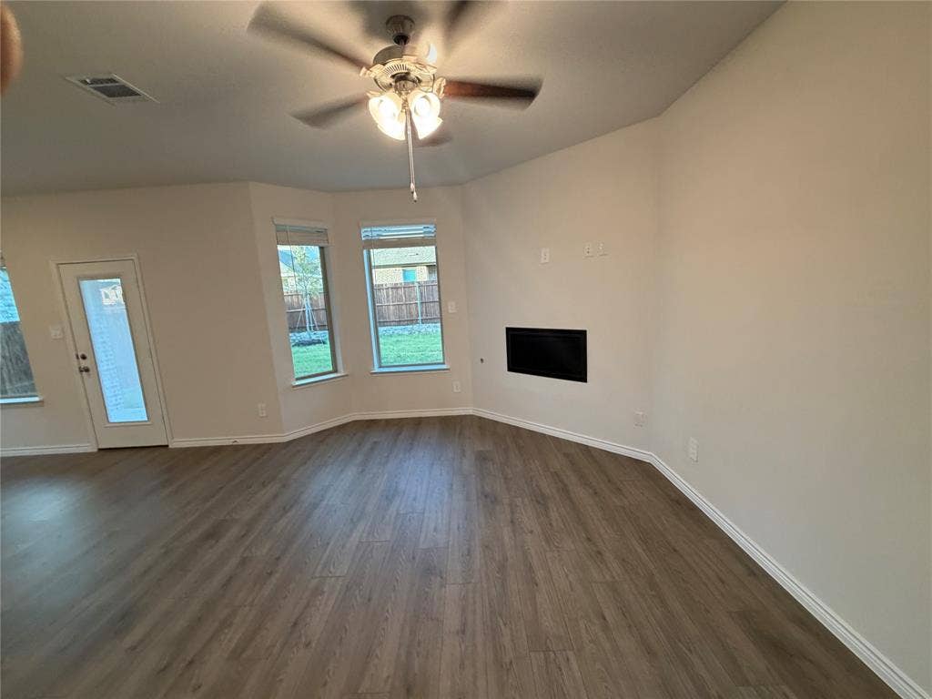 Open interior featuring wood-finish flooring, a recessed fireplace, multi-pane windows, and a ceiling fan with integrated lighting