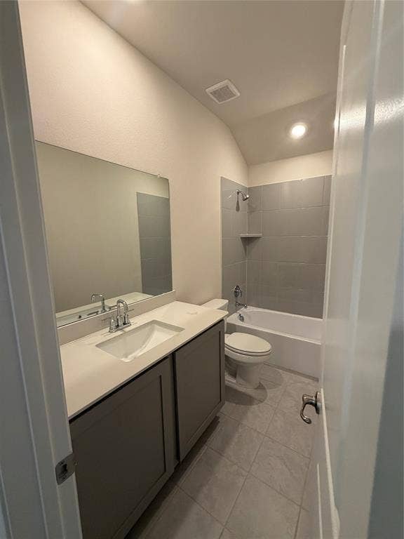 Bathroom featuring a vanity with an integrated basin, countertop, and gray cabinetry, complemented by large-format gray tiled shower surround, soaking tub, and tile flooring