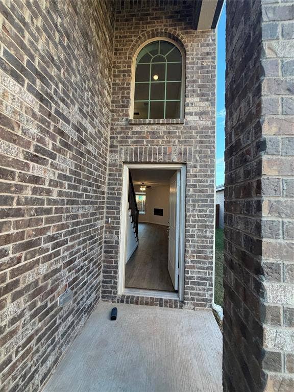 Full brick exterior featuring an arched window with decorative muntins, a concrete entryway, and a hinged entry door